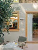 A large timber-framed window and sliding glass door connects the inside and outside living spaces.