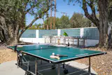 The one-acre grounds include table tennis beneath mature trees, with the property’s distinctive glass-block boundary wall behind.