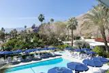 The pool deck at the Herbert W. Burns-designed Holiday House is ringed by navy umbrellas and loungers and looks out over the San Jacinto Mountains.