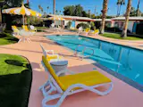 Yellow loungers and striped parasols ring the heated pool, with the single-story bungalows and their colorful doors just steps away.