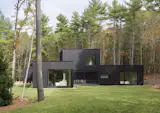 The south elevation reveals the home’s sculptural composition of dark rectangular volumes and voids. Floor-to-ceiling glass openings punctuate the Nakamoto Forestry Gendai Linseed Black yakisugi siding, while the second-floor loft—the family’s self-described "everything room"—rises above a screened porch situated between the two wings.