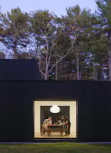 At dusk, the home’s lantern-like quality comes alive, with a large picture window that glows against the charred-wood exterior, framing the dining area.&nbsp;