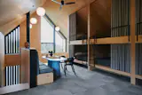 A lofted bunk room with six adult-sized beds offers space for extended family and friends to stay. Built-in mass plywood joinery and gable-end glazing gives the room a warmth and openness unusual for a loft space.