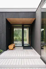 The home is composed of two parallel wings—one housing the main living space, kitchen, and primary bedroom suite; and the other containing the family room, bunk room, and garage.
