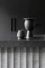 The island has a leathered granite top and granite-tiled face, while black mirror and dark joinery bounce light through the room. The c<span style="font-family: Theinhardt, -apple-system, BlinkMacSystemFont, "Segoe UI", Roboto, Oxygen-Sans, Ubuntu, Cantarell, "Helvetica Neue", sans-serif;">eramic vessels are by Australian artists David Bromley and Belinda Wiltshire.</span>