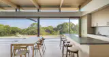 Clerestory windows and retractable glass walls draw daylight deep into the interior, opening the central living space to a tranquil terrace and framed views of Vineyard Sound through the treetops.