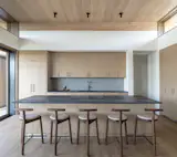 Custom white oak cabinetry designed and supplied by Turkel Design as part of the prefabricated package, reinforces the home’s warm, light material palette.