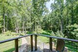 Outdoor, Landscape Lighting, Trees, Walkways, Shrubs, Side Yard, Wood Patio, Porch, Deck, Hardscapes, Stone Fences, Wall, Horizontal Fences, Wall, Wood Fences, Wall, Grass, Decking Patio, Porch, Deck, and Small Patio, Porch, Deck Cantilevered wooden balcony at the Master bedroom  Photo 12 of 16 in A Contemporary Octagon Residence Surrounded by Nature. by Gerardo Hernandez