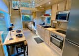 Escaperoo ONE kitchen has custom wood cabinetry, butcher block top, deep stainless sink and designer faucet, long shelving, tall refrigerator/freezer and electric oven + induction cooktop (2 burner) + microwave. Washer / dryer combo. Sealed, sustainably grown Birch interior. Maple composite flooring.