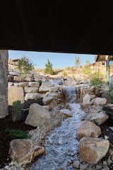 A water feature begins at the top of the terrain and flows under the home to create the perfect ambiance.