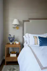 Grasscloth in the Master Bedroom is paired with classically inspired motifs and silhouettes. The side table is from Serena & Lily, the sconce is from Vaughan and the bedding is from Williams Sonoma.