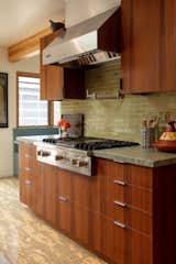 Range cooktop over walnut cabinets, leathered quarzite countertop, and a heath tile backsplash.