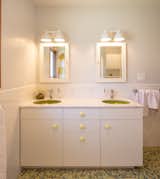 Kids bathroom vanity with dual green sinks and soft yellow pulls.