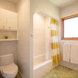 Bath Room, Enclosed Shower, Subway Tile Wall, Undermount Sink, Porcelain Tile Floor, Alcove Tub, Wall Lighting, Marble Counter, and One Piece Toilet Pops of yellow in a bright white bathroom.  Photo 17 of 26 in Ranch 55 by Catherine Garrison Architects