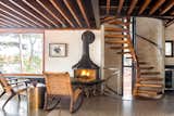 The staircase intersects the living room next to a wood-burning hearth by Andrew White.
