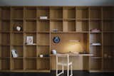 Made of oak, a wall of shelves accommodates an office nook accented with a slim Superlight table lamp from Pablo. 