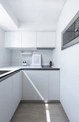 Each apartment's kitchen is modest in size. The all-white palette reflects light around the space.
