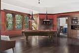 The formal dining room, currently used as a billiards room, features two built-in cabinets, a decorative fireplace with brick detail, and a custom light fixture made out of gramophone speakers.