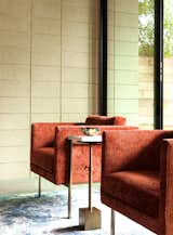 A set of rust-colored chairs contrast with the neutral-toned concrete wall in the living room.