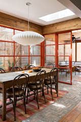 The herringbone brick floor bridges the dining room and screen porch, which are delineated by a set of custom glass-and-steel doors.