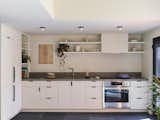 The designers relocated the kitchen to the lower level to create a contained living area for guests. Heath tiles on the counter and backsplash give a midcentury vibe, with updated Blanco Linus appliances and fixtures bringing it into the present.