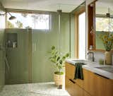 The lower-level bathroom enjoys a door to the outdoors so the family can enter directly after surfing. Green Emser tiles are arranged in a unique alternating pattern, and the shower floor is from Concrete Collaborative.