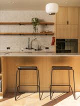 Terracotta tiles in the kitchen lend a sense of warmth. The stools are from Blu Dot and the pendant light is Foscarini.