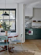 In the dining room, a vintage Danish teak table often doubles as Augustine's writing desk. The chairs are vintage Brooklyn school chairs, and the pendant light is IKEA.