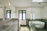 In the primary bathroom, a new shower sits next to a tub with green porcelain tiles from Mutina throughout. The toilet is from Toto and the tub is Duravit. Fixtures are Kohler.  Photo 15 of 23 in Before & After: An L.A. Music Producer’s Latest Collab? Turning a Midcentury Into His Family Home