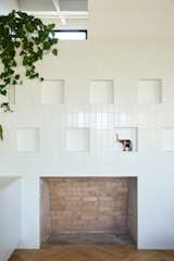 After discovering these fireplace niches hidden behind a faux stone finish, architect Melissa Shin decided to highlight them using a mix of matte and glossy white Fireclay tile. "It's nice because it shimmers a little bit,  Photo 7 of 23 in Before & After: An L.A. Music Producer’s Latest Collab? Turning a Midcentury Into His Family Home