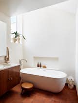 In the upstairs bathroom, the team expanded the footprint by taking some space from an adjacent bedroom. The tile is from Cle, the tub is Claybrook, the faucets are Brizo, and the walnut casework contains custom-designed pulls by Murray Legge Architecture.