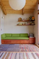 In the living room, the built-in daybed was fabricated by Michael Mellon and Benjamin Winslow out of old growth redwood. The rugs are vintage Japanese and Turkish rugs sourced from Slow Roads. "We chose the green fabric for the daybeds because we wanted it to be retro looking,