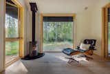 In the living area, a wood stove from Danish company Morso warms the space. The steel fireplace surround was crafted in Mount Vernon, Washington, and large aluminum-clad pine windows frame the exterior environment. The flooring is maple.