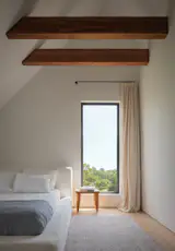 The bedrooms enjoy views of the greenery just outside. The bed is Sixpenny upholstered in a lightweight linen, and the bedside table is Restoration Hardware. The drapes are Belgian linen by TwoPages.