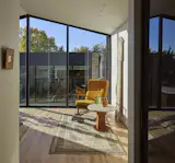 At the back of the house on the second level, the primary suite is awash in daylight from the new glass wall. The chair is vintage Ib Kofod Larsen for Selig.