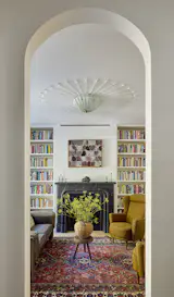 The salon faces the street and enjoys many period-specific details, including a decorative plaster ceiling medallion fabricated by Decorator's Supply Chicago, built-in bookshelves, and a stone mantel. The loveseat is a vintage Afra and Tobia Scarpa for Cassina.