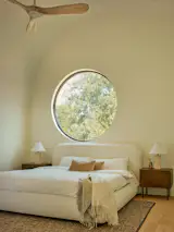 The primary bedroom in the main house features a porthole window and curved ceiling, both of which are visible from the exterior.