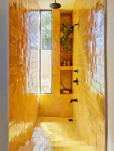 The guest bathroom in the ADU features a sunken Roman tub clad in the same marigold zellige tile as the kitchen in the main house.
