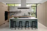 The kitchen features a custom quartzite backsplash and counter with rift-sawn white oak cabinets and a steel cookbook niche. The kitchen tapware is by MGS.