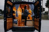 View of the home from the back doors. A small felted pocket acts as a bedside table when the bed is down. Weather proofed cedar paneling keeps the doors from looking industrial. A small sticker on the left back window and additionally on the kitchen window creates a rainbow effect when the sun shines through.