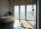 The master bathroom includes a soaking tub and a spectacular water view. The window contains a gas between the panes that fogs up to create privacy when bathing. The floor is slightly graded to slope down to the shower drain for easy cleaning and lip-free shower entry.