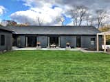 House, garage and pergola form a U-shape onto an elevated terraced area which looks out across a rolling meadow.