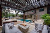 A serene lounge below a custom cypress pergola offers a comfortable viewing spot for taking in the activities in the entire outdoor space.  A stone and tile gas fire pit is surrounded by plush modular seating by Patio Renaissance. 