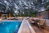 A decorative surface of travertine tile and concrete provides a modern stage for poolside dining.  Luxury handcrafted sling seating by Castelle offers durability and comfort with the perfect spot for entertaining and conversation.  