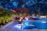 Fire lights the space from pots to a wall feature in this indoor-outdoor living area. Glistening off the calm waters of the modern multi-level pool, the light offers a welcoming invitation to calm and relaxation. 
