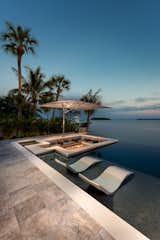 Lounge in luxury on the sun shelf of this infinity pool by Ryan Hughes Design Build. A 12’ x 14’ sunken fire lounge appears to rise out of the waters of the modern pool. 