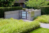 Textured grasses juxtapose an architectural concrete and metal entry gate.
