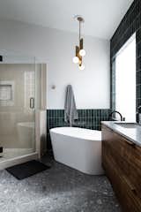 The brass art deco lighting in this bathroom really balances the cool, grey floors.
