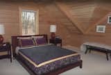 Bedroom, Bed, Carpet Floor, and Table Lighting Upstairs Bedroom. All wood for warmth: Mass Timber walls with matching paneling on the ceiling.  Photo 6 of 8 in Aquarius 1 Mass Timber Geo-Solar home by Enertia® by Enertia Building Systems Inc.