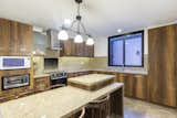Kitchen, Cooktops, Wall Oven, Microwave, Wood Cabinet, Granite Counter, Ceiling Lighting, and Porcelain Tile Floor  Photo 16 of 16 in The Mera House by Pablo Cisneros R.